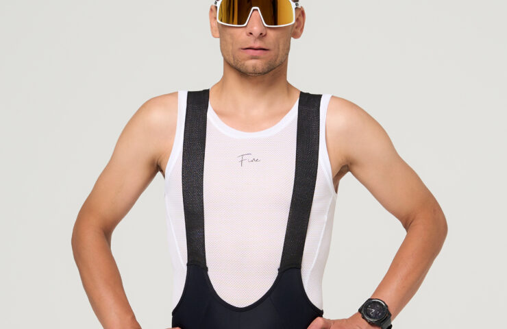 Stojący kolarz w czarnych spodenkach kolarskich oraz białej potówce kolarskiej